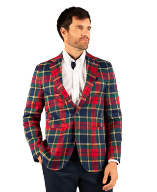 A man wearing a red, navy, and yellow tartan plaid blazer over a white collared shirt, photographed against a plain white background.