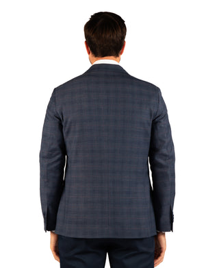 A man viewed from the back wearing a navy blue plaid suit jacket and matching trousers against a plain white background.
