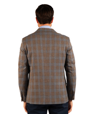 A man viewed from behind wearing a brown and gray plaid blazer over a light blue dress shirt and dark trousers, set against a plain white background.